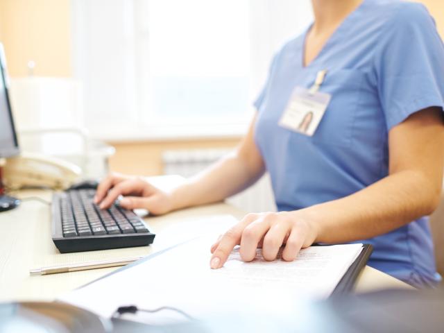 Woman in scrubs using computer