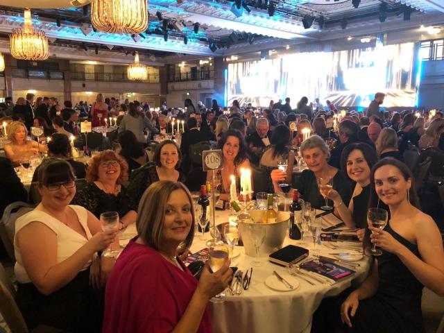 Zoe and her team at the awards ceremony sat around a table holding their drinks