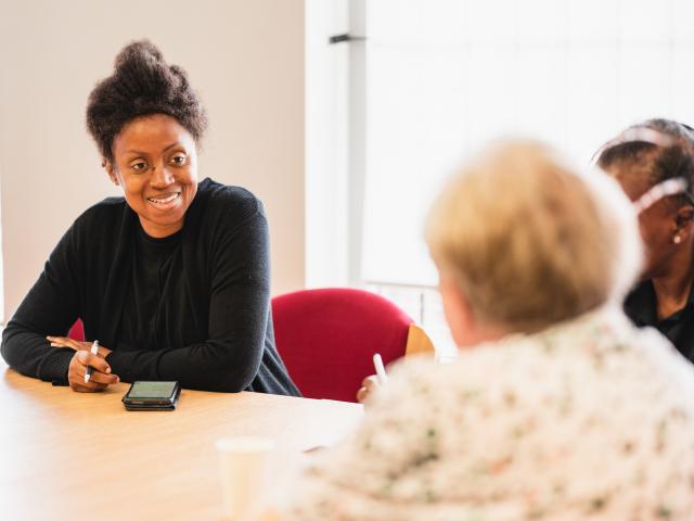 A woman talking to elderly residents of a care home.