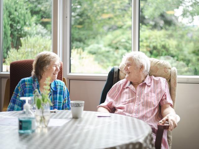 An elderly gentleman and woman sitting next to each other and talking. 