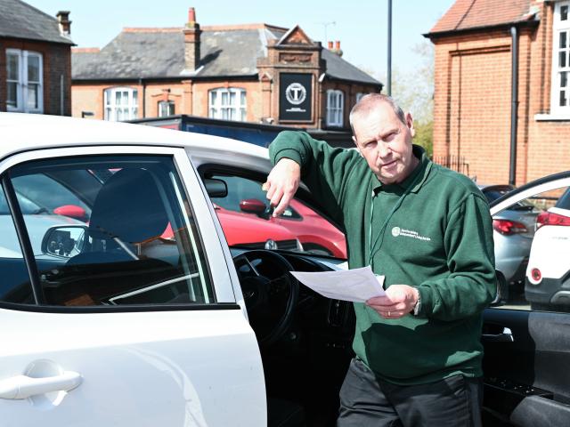 A man in green sweater standing next to a car.