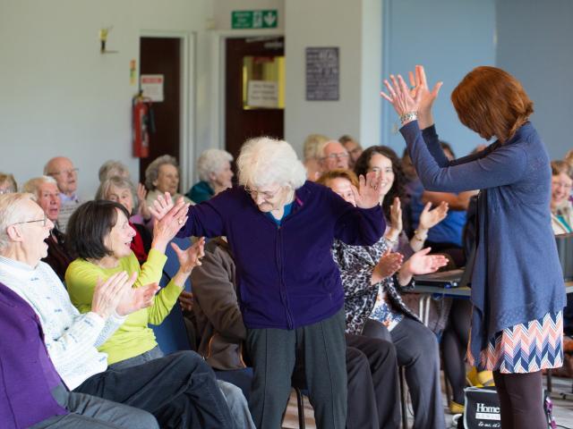 Woman with grey hair dancing with group