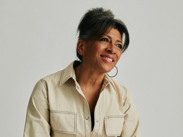 A woman with darker skin and black hair smiling towards the camera. 