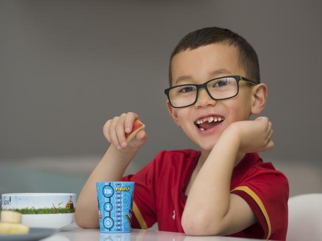 A boy in red shirt smiling at the camera.