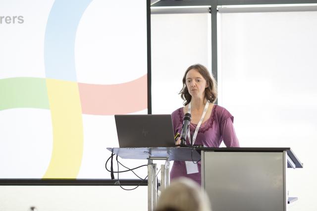 female speaker talking to audience about research