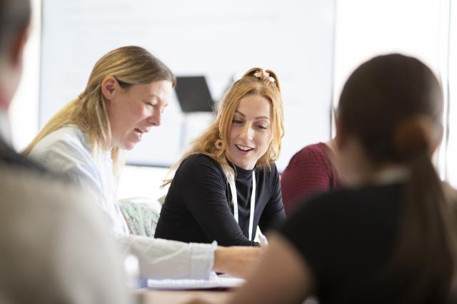 Two women sat at table discussing research