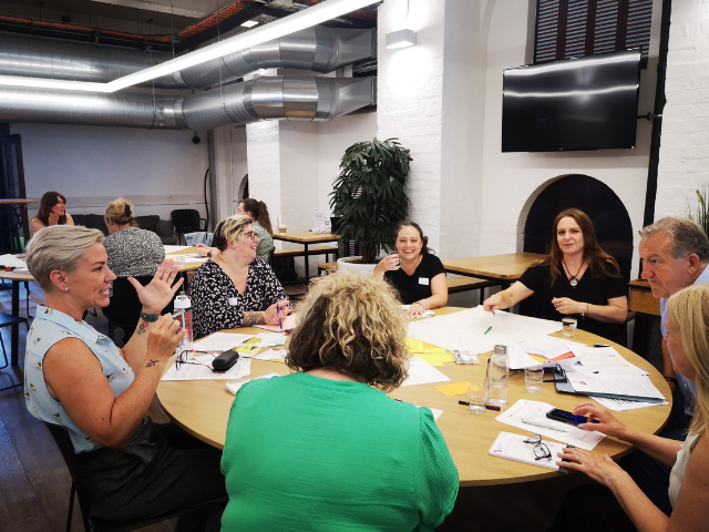 A group of people sitting around a table a discussing research.