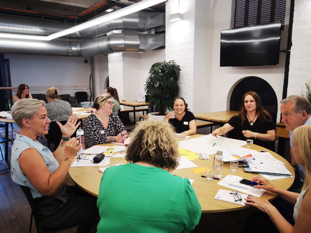 A group of people sitting around a table a discussing research. 