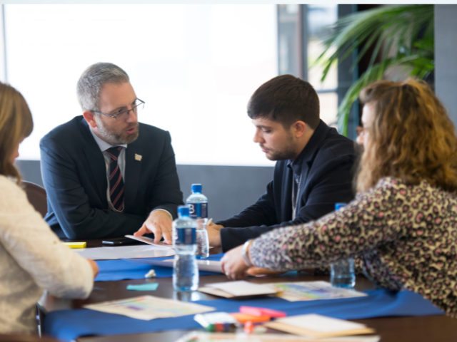 A group of people sitting around a table a discussing research. 