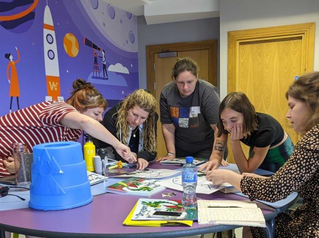 five female scientists sat around a table working together