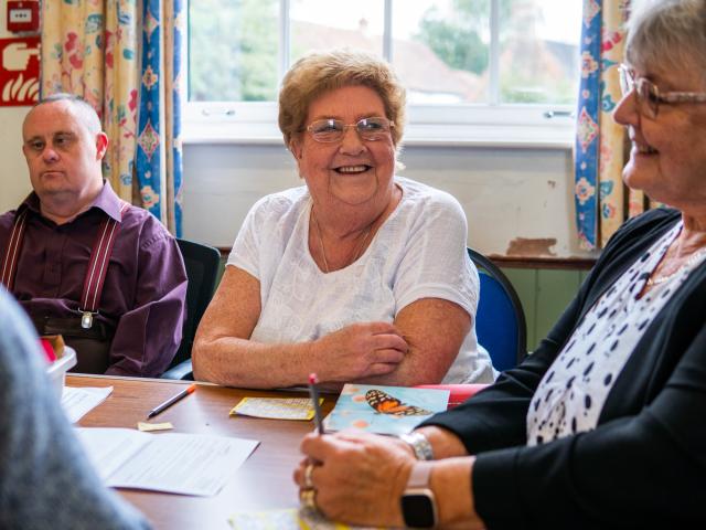 An elderly woman sitting next to another one with a man to their left. 