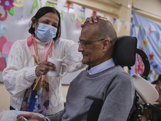 Woman caring for a man on a wheelchair. 