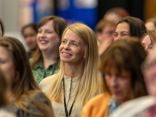 Woman smiling in conference audience