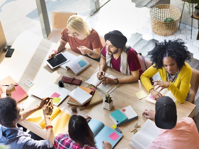 A group of people sitting around a table a discussing research.
