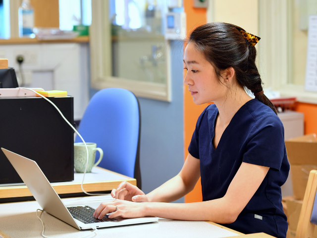 Woman using a computer wearing scrubs