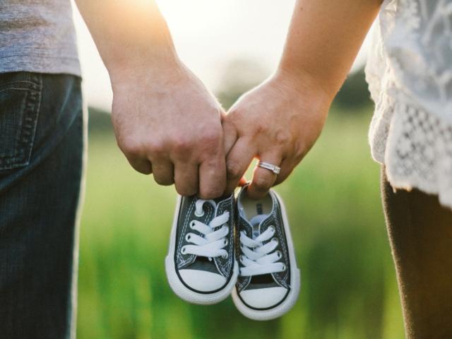 two_people_holding_baby_shoes