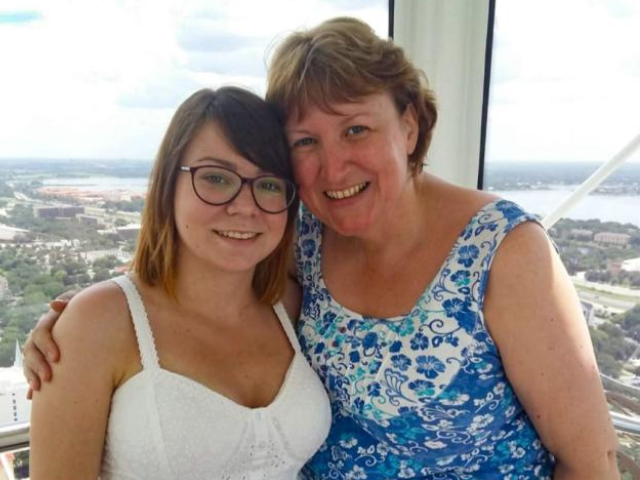 Two women stood together, one with her arm around the others shoulder
