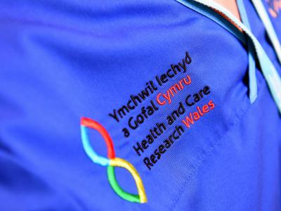 Logo Ymchwil Iechyd a Gofal Cymru ar wisg nyrsys