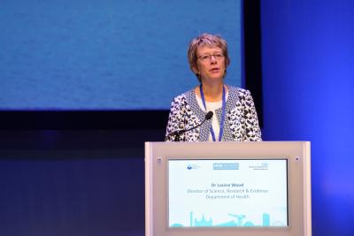 Woman stood behind podium on stage speaking