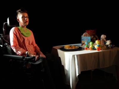 a_women_in_pink_in_a_wheelchair_next_to_a_white_table