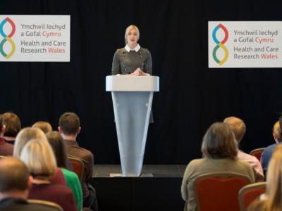 a_woman_standing_at_a_podium_presenting_at_a_conference